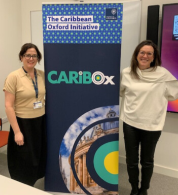 Professor Sarah Quesada and Professor Maria Blanco smiling by banner