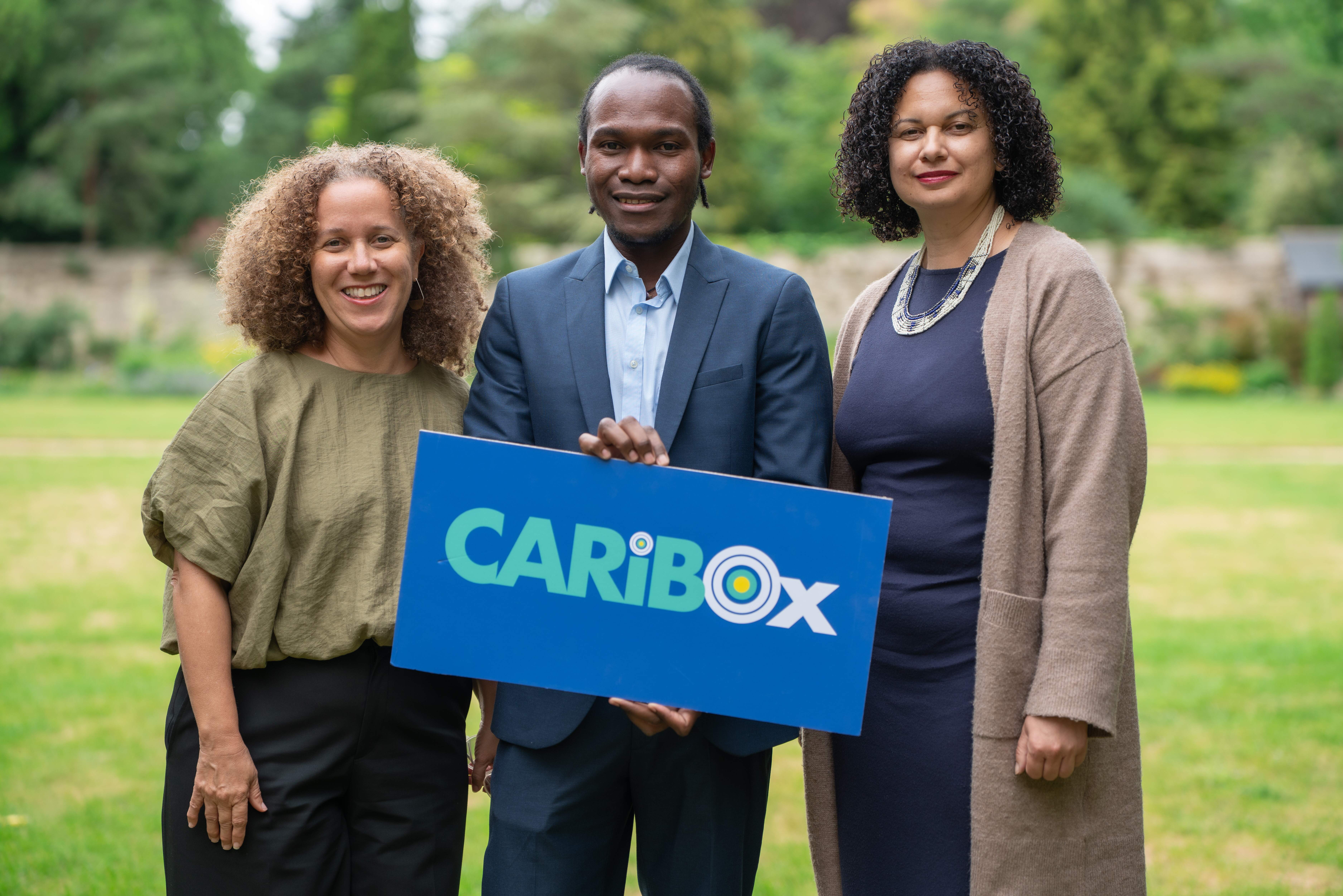 CaribOx 2026 Visitors holding logo sign