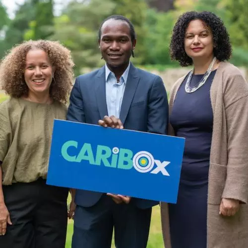 CaribOx 2026 Visitors holding logo sign